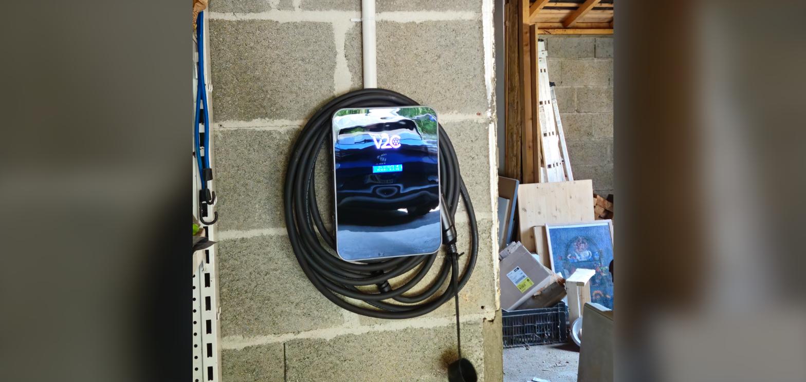 Borne de recharge pour voiture électrique fixée sur un mur de garage avec câble enroulé, installation United Borne près de Cholet