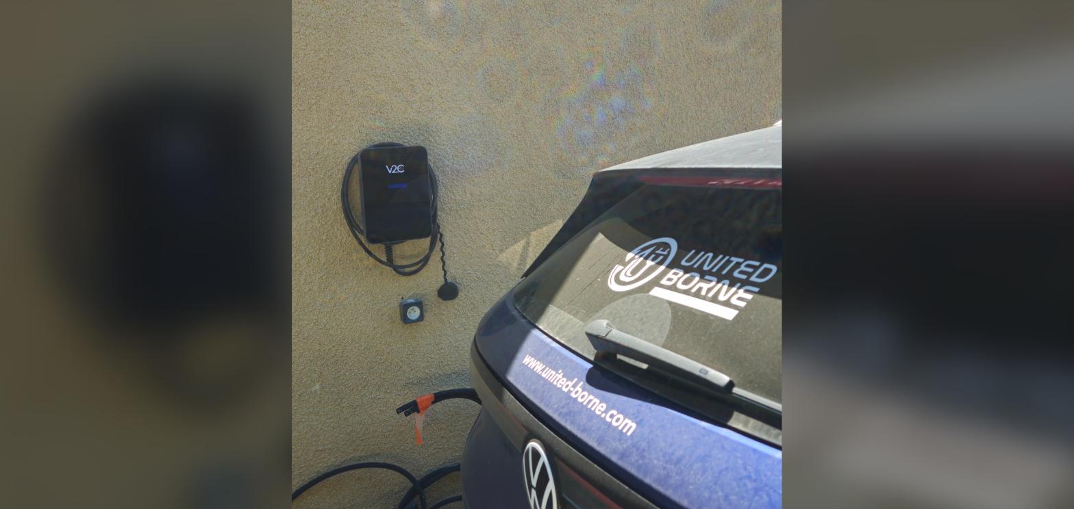 Véhicule United Borne stationné devant une borne de recharge murale installée par l’entreprise près de Cholet