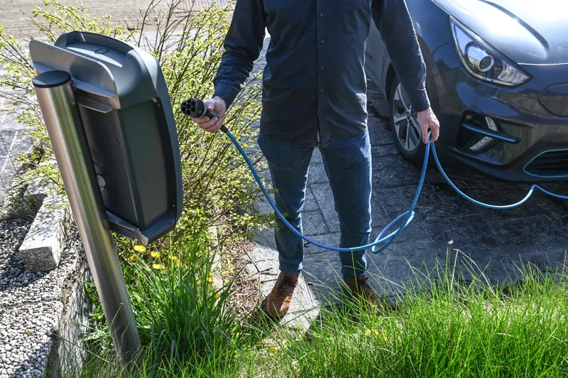 Personne branchant sa voiture electrique sur une borne de recharge