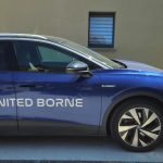 Voiture électrique aux couleurs de United Borne branchée sur une borne de recharge murale installée près de Cholet